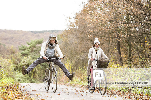 Senior couple doing a bicycle trip with dog in autumn