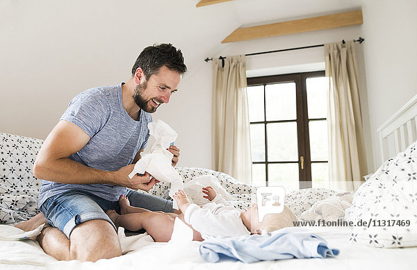 Father changing baby's diapers on bed