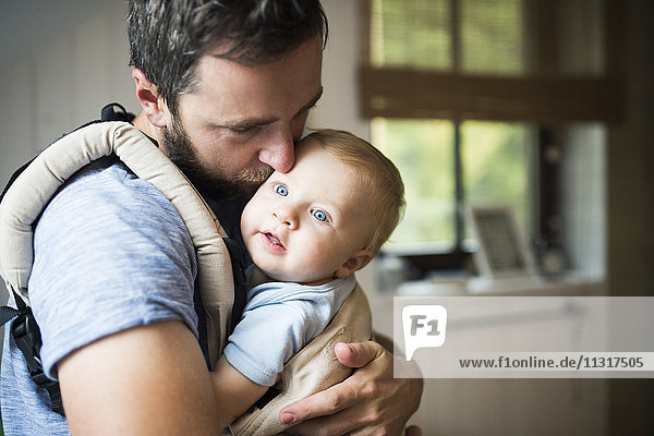 Father cuddling with baby in baby carrier