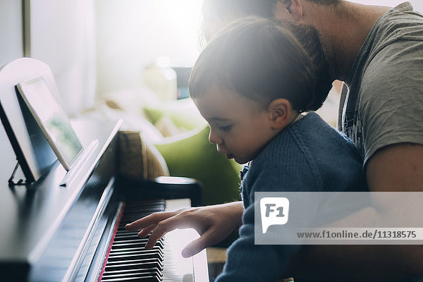 Child and his father playing piano