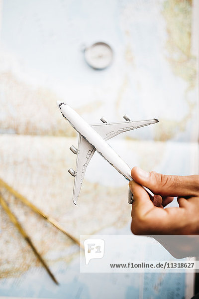 Handgehaltenes Flugzeugmodell vor der Weltkarte