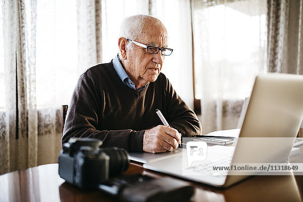Senior photographer working with laptop at home