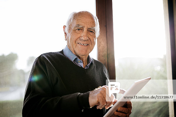 Porträt eines lächelnden älteren Mannes mit vor dem Fenster stehender Tafel