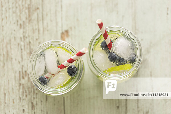 Gläser mit aufgegossenem Wasser mit Limette  Heidelbeeren und Eiswürfeln