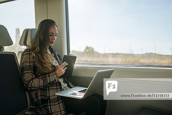 Geschäftsfrau im Zug mit Notebook und Laptop