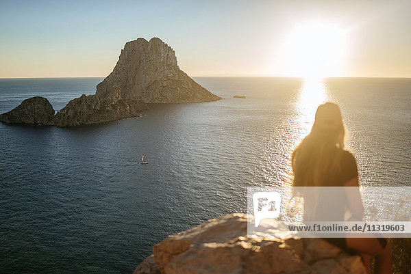 Spanien  Ibiza  Frau mit Blick auf das Meer und die Insel Es Vedra bei Sonnenuntergang