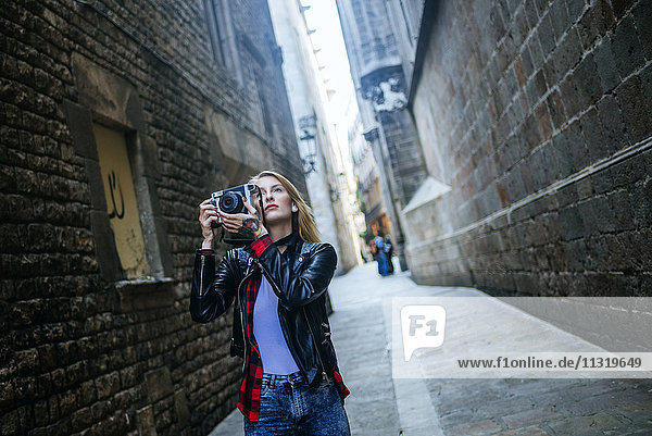 Spain  Barcelona  young woman taking pictures with reflex camera at Gothic Quarter