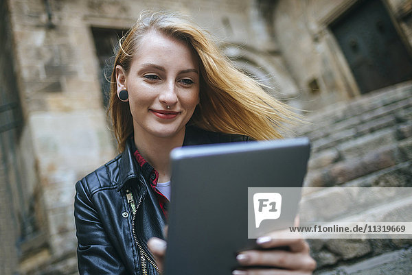 Spain  Barcelona  portrait of smiling young woman looking at tablet