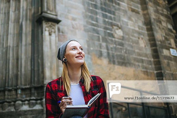 Spain  Barcelona  smiling young woman with notebook