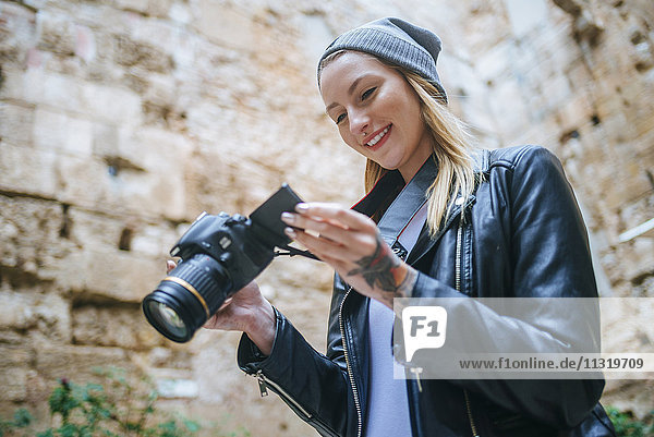 Lächelnde junge Frau beim Betrachten von Fotos auf der Kamera