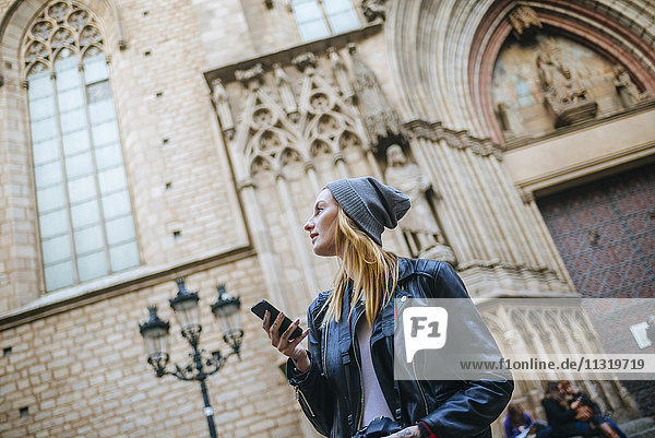 Spain  Barcelona  young woman with mobile phone watching something