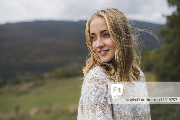 Lächelnde junge Frau mit Pullover im Freien