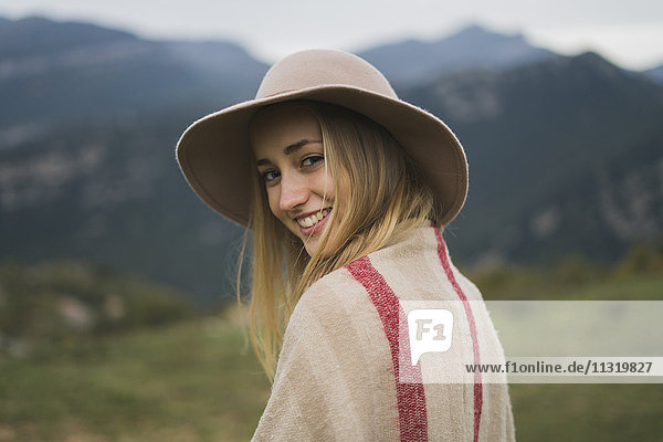 Porträt einer lächelnden jungen Frau mit Hut im Freien