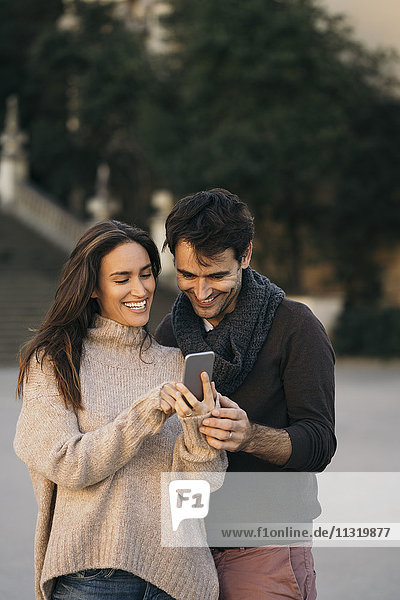 Laughing couple looking at cell phone