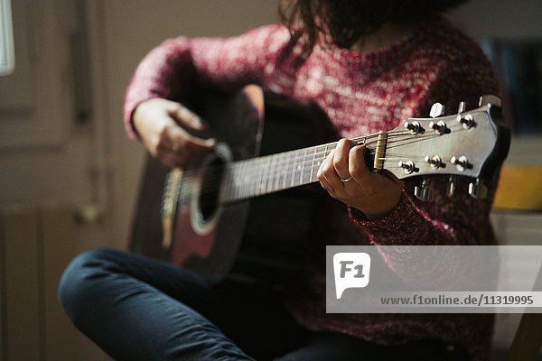 Junge Frau spielt zu Hause Gitarre