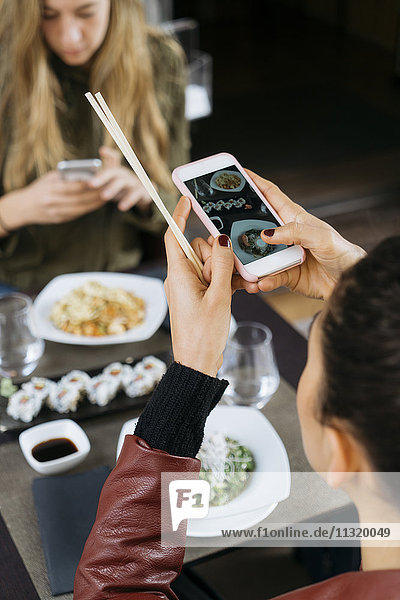Woman taking picture of sushi in a restaurant  partial view