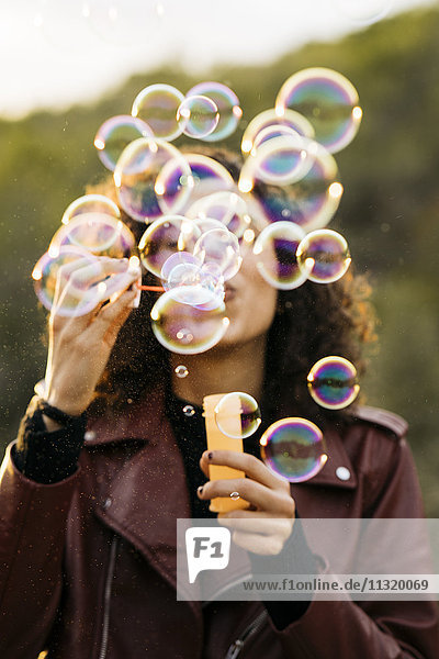 Young woman blowing soap bubbles