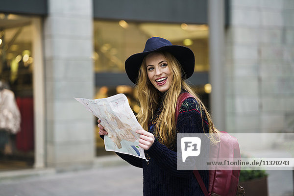 Portrait eines glücklichen Touristen mit Stadtplan und Rucksack