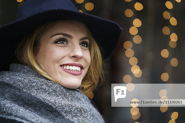 Porträt einer lächelnden jungen Frau mit Hut und Schal