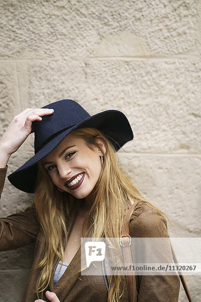 Porträt einer lächelnden Frau mit Lederjacke und blauem Hut