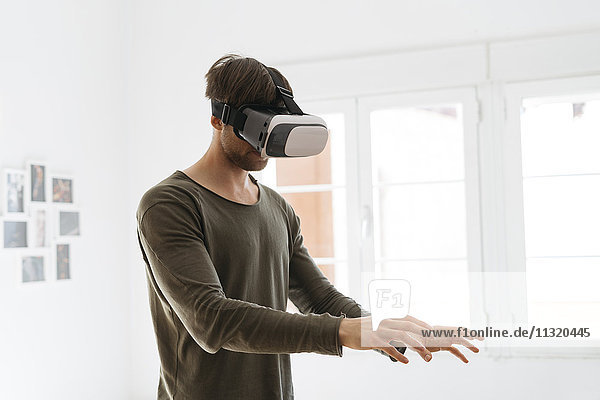 Young man wearing virtual reality glasses at home