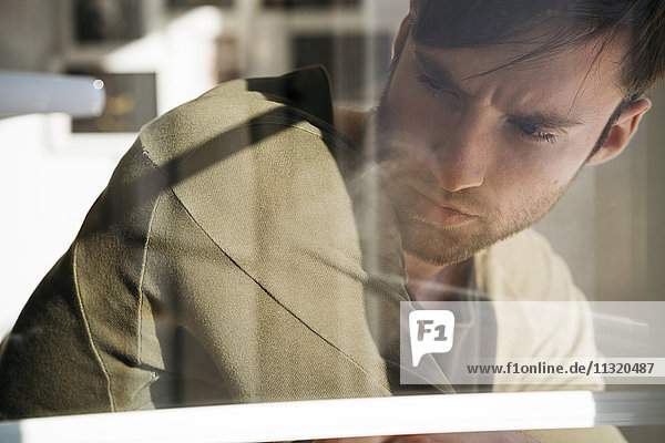 Young man lost in thought behiing windowpane