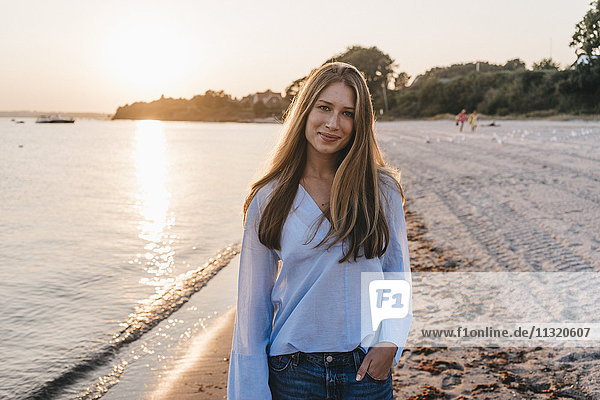 Smiling young woman on the beach at twilight