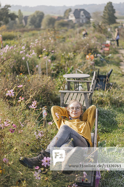 Junge Frau entspannt sich im Hausgarten