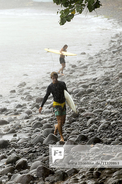 Indonesien  Bali  zwei Surfer mit Surfbrettern im Regen