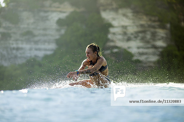 Indonesien  Bali  Frau auf dem Surfbrett im Meer sitzend