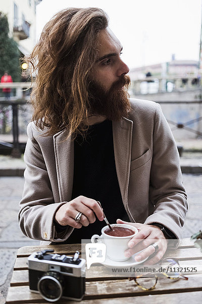 Stylish young man at a street cafe looking around