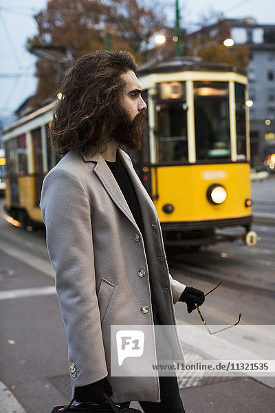Stylish young man standing at tram stop