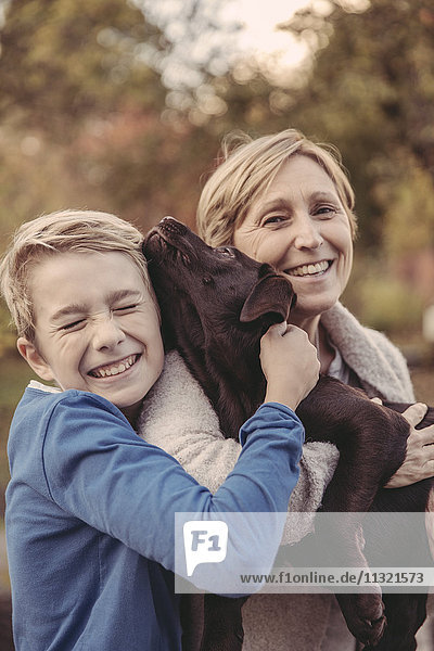 Junge und Frau kuscheln mit Labrador Retriever