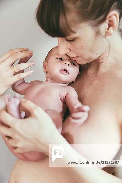 Nude mother holding her newborn baby