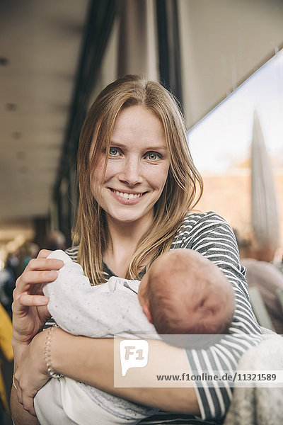 Porträt der lächelnden Mutter mit Baby im Café