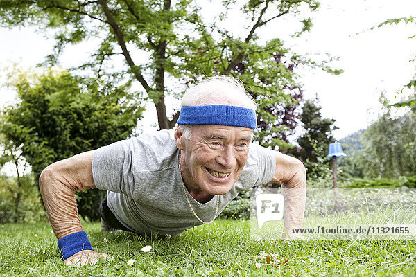 Senior Mann macht Liegestütze für Fitnesstraining im Garten