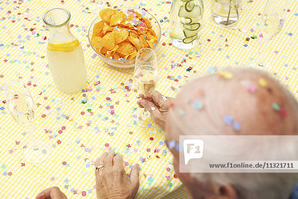 Seniorenfeier am Tisch mit Wasser  Champagner und Kartoffelchips