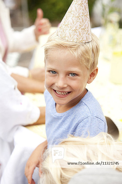 Blonder Junge mit Partyhut auf der Geburtstagsfeier