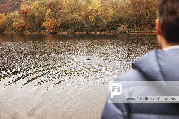 Mann mit Hund im Herbst im See schwimmend