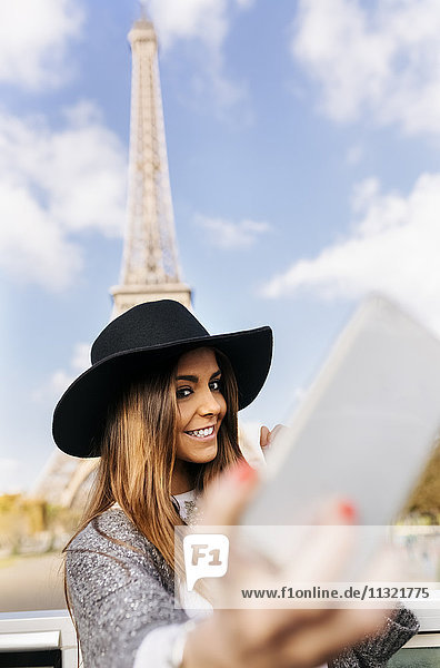 Frankreich  Paris  lächelnde Frau mit einem Selfie vor dem Eiffelturm