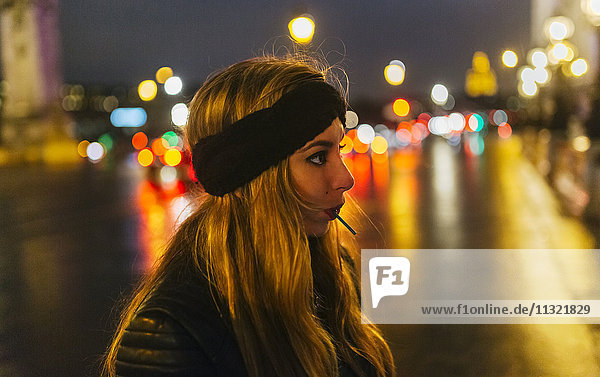 Frankreich  Paris  junge Frau mit Lolli bei Nacht auf der Straße