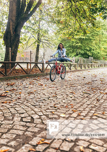 Happy young woman riding a bike in a park
