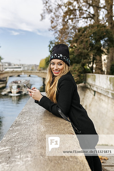 Frankreich  Paris  Portrait einer glücklichen jungen Frau mit Handy