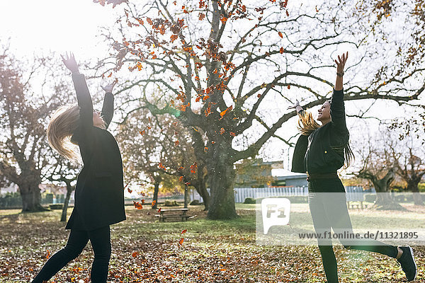 Zwei fröhliche junge Frauen  die sich im Herbst im Park amüsieren.