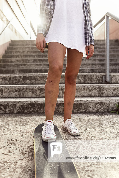 Beine der jungen Frau mit Skateboard