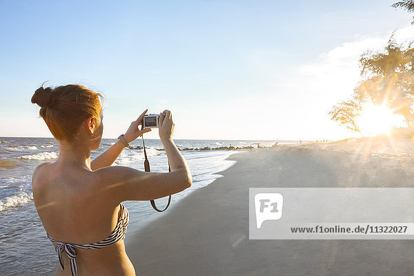 Frau am Strand fotografiert mit ihrer Kamera