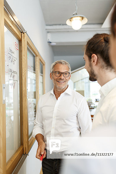 Smiling businessman looking at colleagues in office