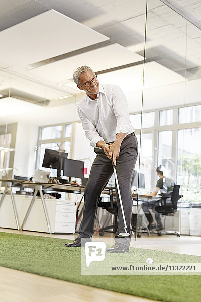 Geschäftsmann spielt Golf im Büro