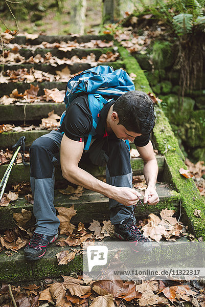 Wanderer sitzt auf einer Treppe und schnürt seine Schuhe.