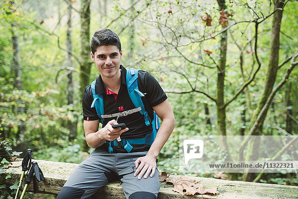 Portrait of smiling hiker with smartphone in nature